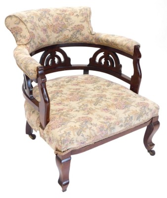 A late 19th/early 20thC walnut tub shaped chair, upholstered in floral fabric, on cabriole legs.