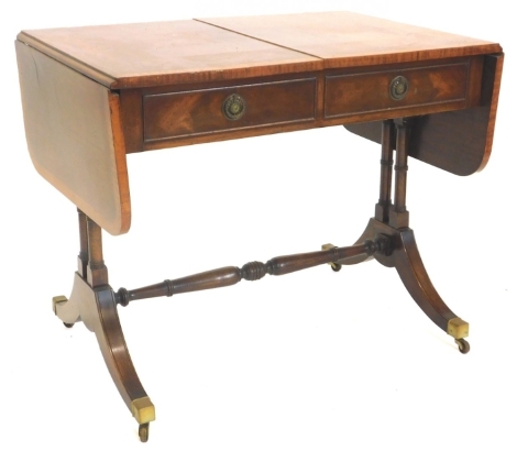 A mahogany and satinwood crossbanded sofa table, the rectangular top with rounded corners above two frieze drawers opposing false drawers, on turned end supports with splayed legs and brass castors, 75cm high, 91cm wide.