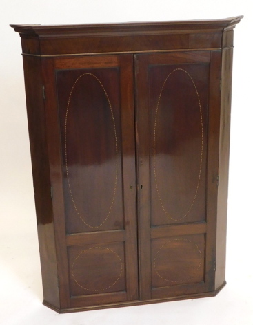 A 19thC mahogany and chequer banded hanging corner cabinet, with a moulded cornice above two doors, each with two panels enclosing shelves, 111cm high, 87cm wide.