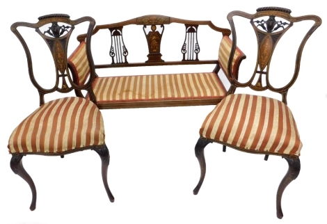 An Edwardian mahogany and marquetry salon sofa, with two pierced splats flanking a central inlaid splat, decorated with putti, ribbons, etc., with padded sides and seat, on splayed legs, and a pair of associated side chairs.