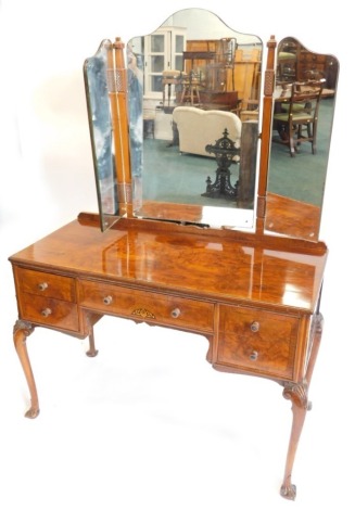 An early 20thC figured walnut dressing table, with triple mirrored back, the base with five drawers, each with faceted and turned handles, on carved cabriole legs, 114cm wide.