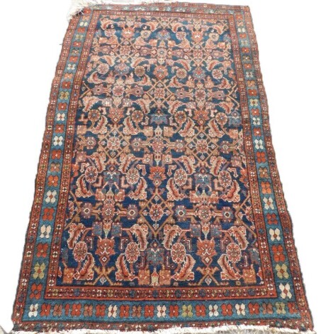 A Persian rug, with an all over design of flowers, leaves, etc., in red and pale blue, on a navy ground with one wide and two narrow borders, 116cm x 193cm.