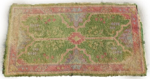 A Turkish rug, with a central pink pole medallion on a green ground, with one wide and multiple borders, (AF), 98cm x 174cm.