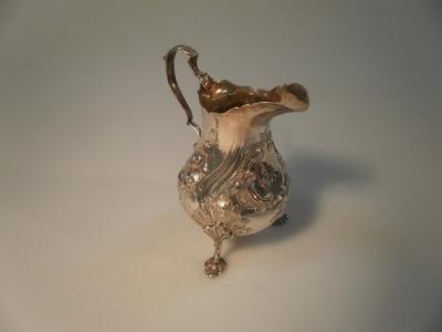 A Victorian silver pear shaped cream jug embossed with rococo decoration