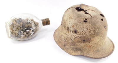 A German WWI M16 helmet (AF), together with a bottle containing lead shot. (2)