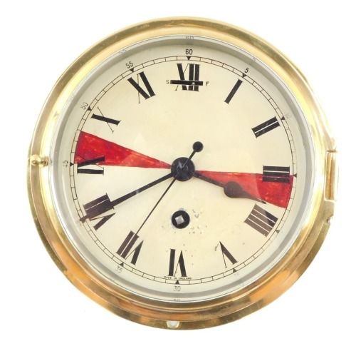 An early 20thC brass ship's clock, enamel dial bearing Roman numerals, with key, 20.5cm diameter.