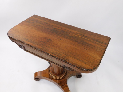 A Regency rosewood fold over card table, the frieze with acanthus scroll carving, raised on a turned column, over a quatrefoil base, on castors, 73.5cm high, 92cm wide, 44.5cm deep. - 2