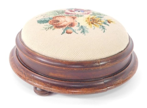 A Victorian mahogany foot stool, with floral wool work upholstery, raised on three turned feet.