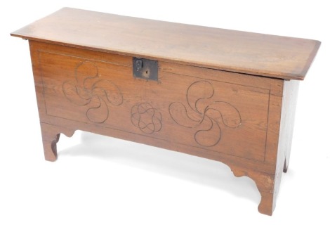 An oak coffer, the rectangular planked top with a chamfered edge, enclosing a candle box with metal lock, the front carved with paterea and stylised flower head design on bracket feet, 60cm high, 117cm wide.