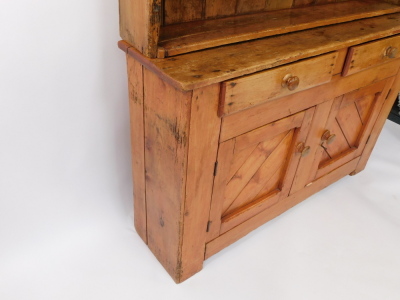 A reclaimed pine dresser, with a planked top above two frieze drawers and two paneled doors, each with turned wood handles on bracket feet, the associated plate rack with a petalated frieze, above three shelves, 198cm high, 130cm wide. - 4