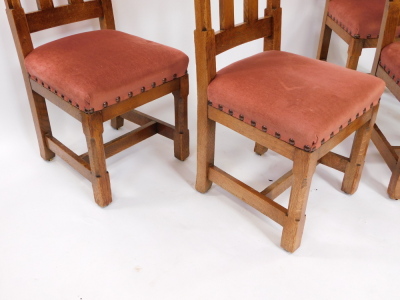 A set of four late 19thC Liberty & Co oak dining chairs, each with a Gothic shaped back, pink upholstered padded seat, on chamferred legs with H stretcher, bone labelled to underside. - 3