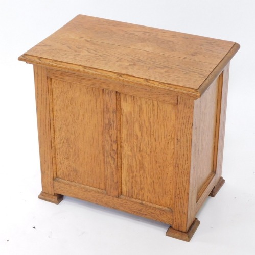 An oak Arts & Crafts workbox, the hinged lid with a moulded edge, above a paneled front on block feet, 51cm wide.