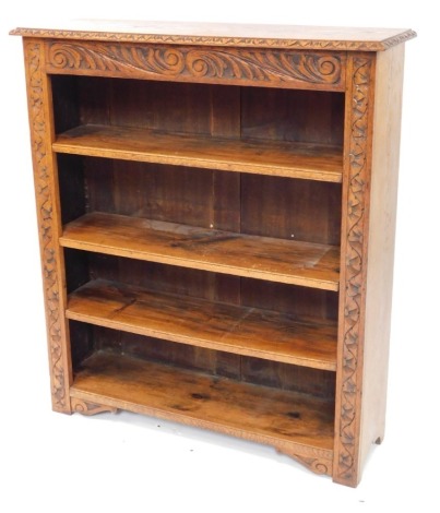 A carved oak open bookcase, the top with a moulded edge, above a frieze decorated with foliate scrolls, and three adjustable shelves, on stiles, 120cm high, 106cm wide.