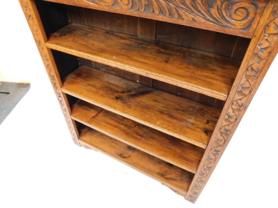 A carved oak open bookcase, the top with a moulded edge, above a frieze decorated with foliate scrolls, and three adjustable shelves, on stiles, 120cm high, 106cm wide. - 3