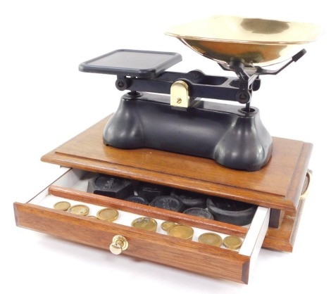 A set of brass and cast iron kitchen scales, raised on a twin handled mahogany base, with drawer opening to reveal cast iron and brass weights, 10g - 500g, and 1/4oz - 1lb.