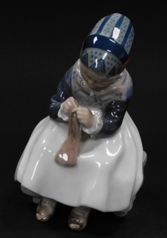 A Royal Copenhagen porcelain figure of a girl, modeled seated knitting a scarf, No 1314, printed and painted marks.