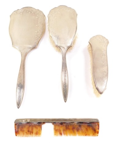 A silver backed four piece dressing table set, with engine turned decoration and engraved floral and foliate decoration, comprising hand mirror, clothes and hair brushes, and a comb, Birmingham 1959.