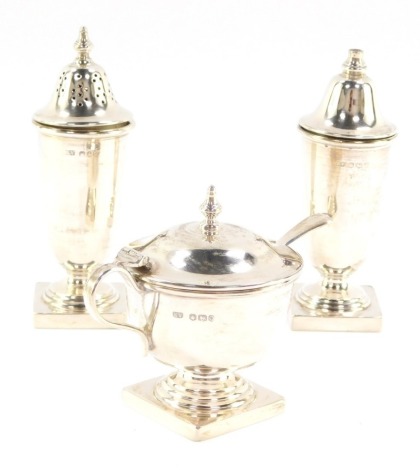 A silver three piece condiment set, of Neo Classical form, comprising mustard pot with spoon and blue glass liner, salt and pepperette, Sheffield 1956, 5.08oz,