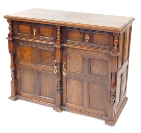 A 19thC oak side cabinet, the top with a moulded edge, above two paneled doors, each with brass tear drop handles, flanked by short turned pillars, above two doors, flanked by further pillars, on shallow feet, 95cm high, 120cm wide, 55cm deep.