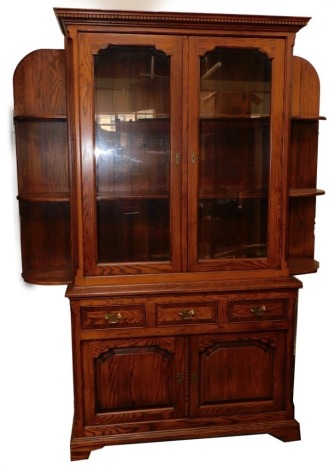 An oak bookcase, the top with a moulded and dentil cornice, above two glazed doors, enclosing shelves, the base with a moulded edge, above three cross banded drawers, and two paneled doors, on bracket feet, 210cm high, 104cm wide, 43cm deep, together with