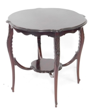 An Edwardian mahogany occasional table, the circular top with a moulded shaped edge, on leaf carved supports, with under tier, 72cm high, 71cm wide.