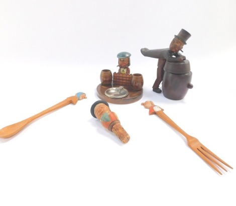 A Continental early 20thC carved wooden figural bottle stopper, together with a figural mounted smoker's compendium jar and cover, and a pair of salad servers.