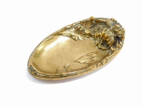 A brass pin dish, with raised detailing of flowers and leaves, on three stepped feet, 16cm wide.