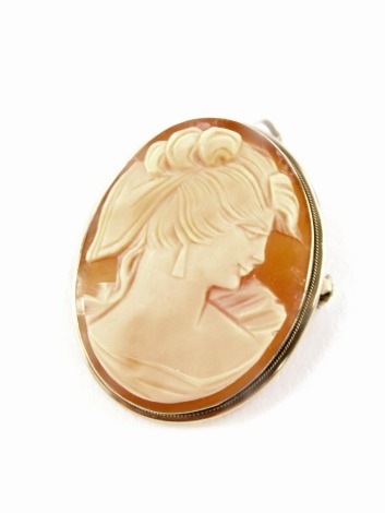 An oval shell cameo brooch, depicting a quarter profile of a female, looking right, in a yellow metal pendant pin back, unmarked, 3.5cm x 3cm, 7.4g all in.