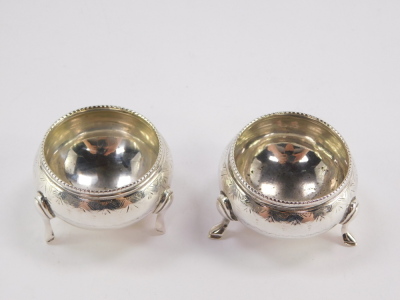 A pair of Victorian miniature circular silver salts, with a reeded collar and hammered detailing with vacant cartouche, on tripod feet, Sheffield 1876, 3.5cm high, 2½oz. - 2