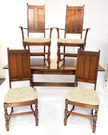 An Ercol oak extending dining table, on end supports, together with six dining chairs, each with a paneled back and a carved frieze, comprising a pair of carvers and four single chairs, table 175cm extended. (7)