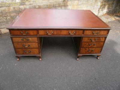 A early 20thC mahogany partner's desk with a brown leatherette inset above