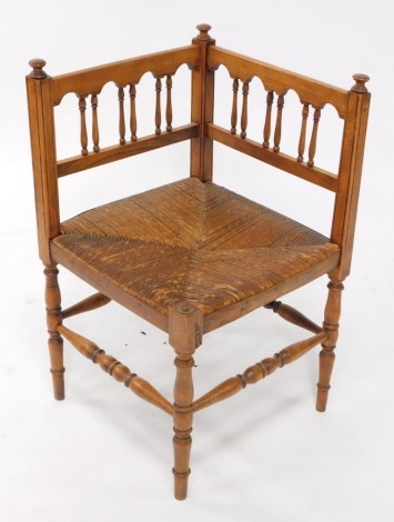 An early 20thC oak and beech corner chair, with a rush seat on turned supports.