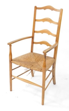 A stained beech ladder back open armchair, in Arts & Crafts style with a rush seat, on turned supports.