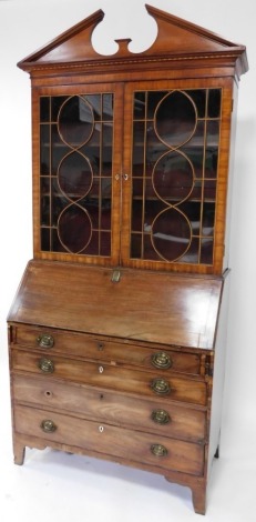 A George III mahogany and box wood strung bureau bookcase, the associated top with a break front cornice and a parquetry frieze, above two astragal glazed doors enclosing adjustable shelves, the base with a paneled fall, enclosing a fitted interior, above