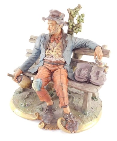 A Capo di Monte porcelain figure of a drunken tramp, seated on a bench, 25cm wide. (AF)