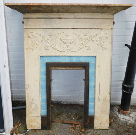 An early 20thC cast iron fire place, decorated with a central urn, flowers, leaves, etc., with a blue tiled surround, 137cm high, 119cm wide. (AF)