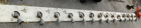 A set of fourteen brass and wrought iron servant's bells, mounted on to a cream painted board, with some fixings, the board 423cm long overall.