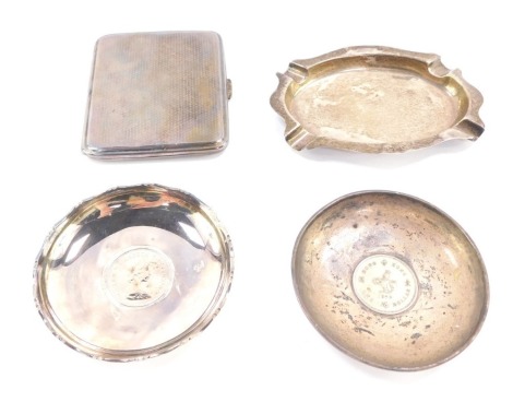 Silver, to include a George V engine turned cigarette case, London 1929, an oval ash tray, two silver pin dishes, each inset with a coin, stamped Sterling, 4 3/4oz overall. (a quantity)