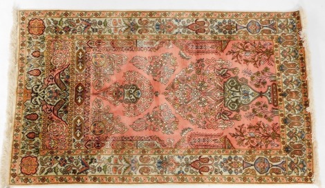 A Persian silk prayer rug, pink ground, the mihrab decorated with a vase of flowers, hanging lantern, and further flowers, etc., within a repeating floral border, 158cm x 93cm.