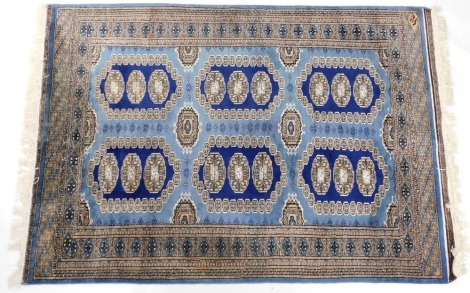 A Pakistani blue ground rug, decorated with six medallions, each containing three guls, within a repeating geometric border, 194cm x 132cm.