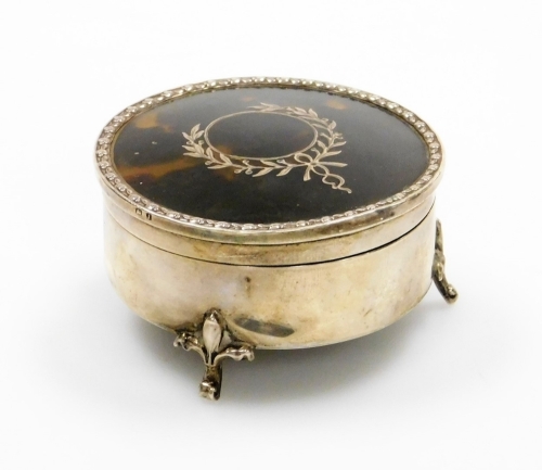 A George V silver and tortoiseshell trinket box, the circular top with tortoiseshell inlay, and applied silver detailing on a floral border, on three stylised fleur de lis feet, maker E.S.Barnsley, Birmingham 1910, 6cm diameter, 2½oz.