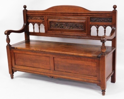 A late Victorian walnut settle, with galleried scroll back and fluted column supports, 96cm high, 137cm wide, 46cm deep.