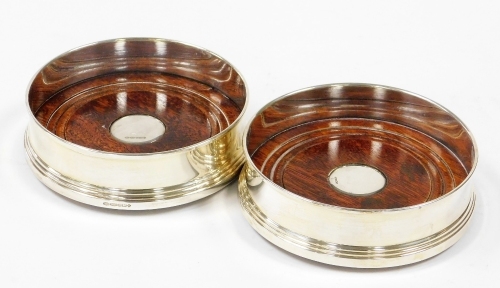 A pair of silver wine coasters, each with wooden base and silvered rim, Birmingham Millennium 2000, 13cm diameter.