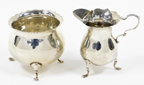 A George V Mappin & Webb silver sugar bowl and milk jug, with wavy rim, each on three feet, London 1926, 4¾oz. (2)