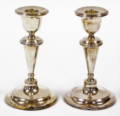 A pair of Edward VII silver dwarf candlesticks, each with a taper stem and stepped base with weighted bases, Birmingham 1906, 15cm high, 23½oz gross.