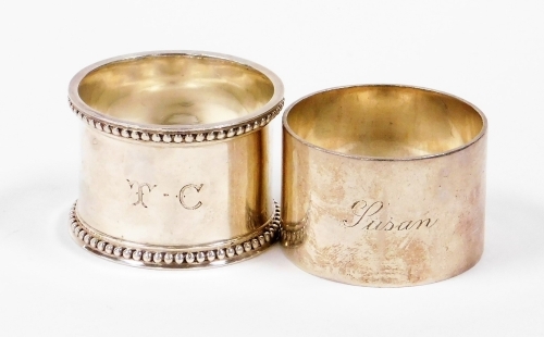 Two silver napkin rings, to include one with floral design border bearing the initials TC, Sheffield 1908, together with another of plain design stamped Lusam, Sheffield 1947, 4oz. (2)
