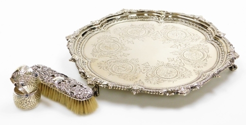 A group of silver and silver plated wares, to include a Victorian silver plated salver, with tripod ball and claw feet and engraved detailing of flowers, together with a silver backed dressing table brush (AF) and a pair of silver plated candlesticks. (4)