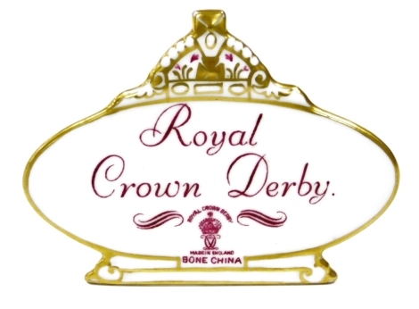 A Royal Crown Derby retailers' plaque, with crown top on an oval plaque with purple stamp and writing, 10cm wide.