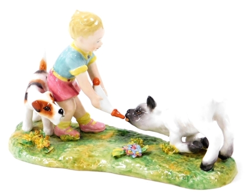 A Royal Crown Derby figure group, of a child feeding a lamb with dog, with red stamp to underside, 16cm wide.