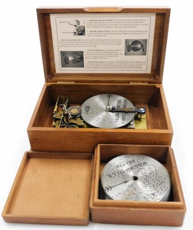 A portable early 20thC disc musical box, with various additional discs, enclosed in two boxes.